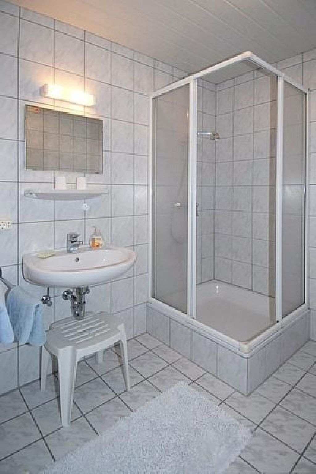 Ein Badezimmer mit einem weißen Waschbecken, einem Spiegel und einer Duschkabine.