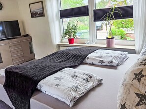 A bedroom with a bed, a TV, a dresser, and a window with blinds. - Apartment mit Terrasse am Südstrand by Interhome (Borkum)