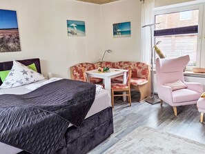 Un dormitorio con cama, sofá, silla, mesa y ventana.