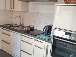 Una cocina con lavavajillas, cafetera y horno.
