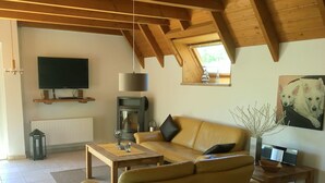 Een gezellige woonkamer met een bank, een televisie, een open haard en een schilderij van honden.