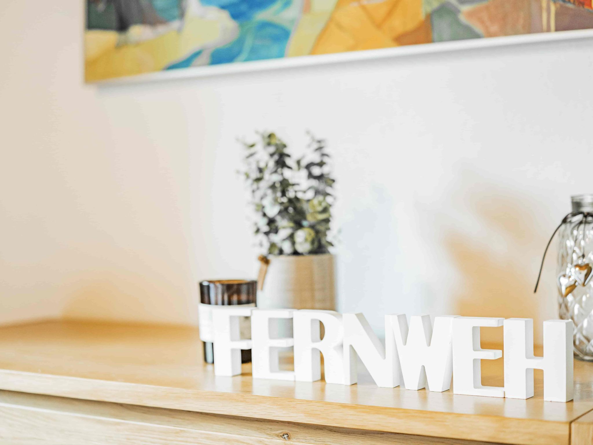 A wooden shelf with white letters spelling "FARWEH" and a small potted plant.