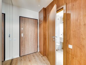 Ein Zimmer mit Holztüren, einer weißen Wand und einem Fliesenboden.