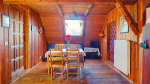 Eine Holzhütte mit Essbereich, inklusive Tisch, Stühlen, einem kleinen Fenster und einem Heizkörper.