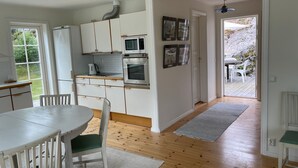Eine moderne Küche mit weißen Schränken, einer Mikrowelle und einem Backofen. Ein Essbereich mit Tisch und Stühlen ist ebenfalls vorhanden.