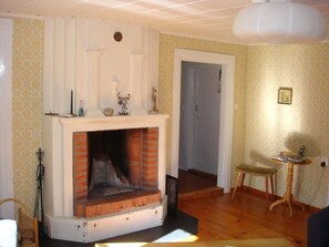 A living room with a fireplace, patterned wallpaper, a door, a small table, and a chair. - Vacation home Nymåla by Interhome (Hultsfred)