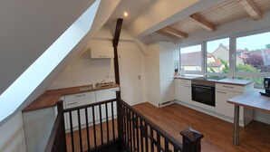 Een moderne keuken met een houten aanrecht, witte kastjes en een groot raam met uitzicht op de omgeving.