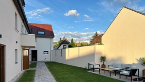 Een modern huis met een verhard pad dat leidt naar een gazon en een terras.