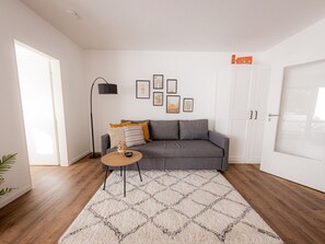 A modern living room with a grey sofa, a round coffee table, and a patterned rug. - Come4Stay Passau - Apartment Seidenhof - Balkon by Interhome (Passau)