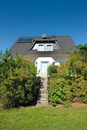 A house with a sloped roof, a satellite dish, and a white garage door. - Vacation home  by Interhome (Bansin)
