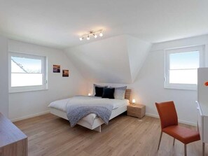 A modern bedroom with a bed, bedside tables, a desk, and a chair. - Vacation home  by Interhome (Bansin)