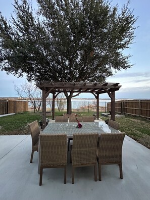 An outdoor patio with a pergola, a table, and wicker chairs. - Lakeside Getaway Near AT&T Stadium, Globe Life, Six Flags & Epic Waters (Grand Prairie)
