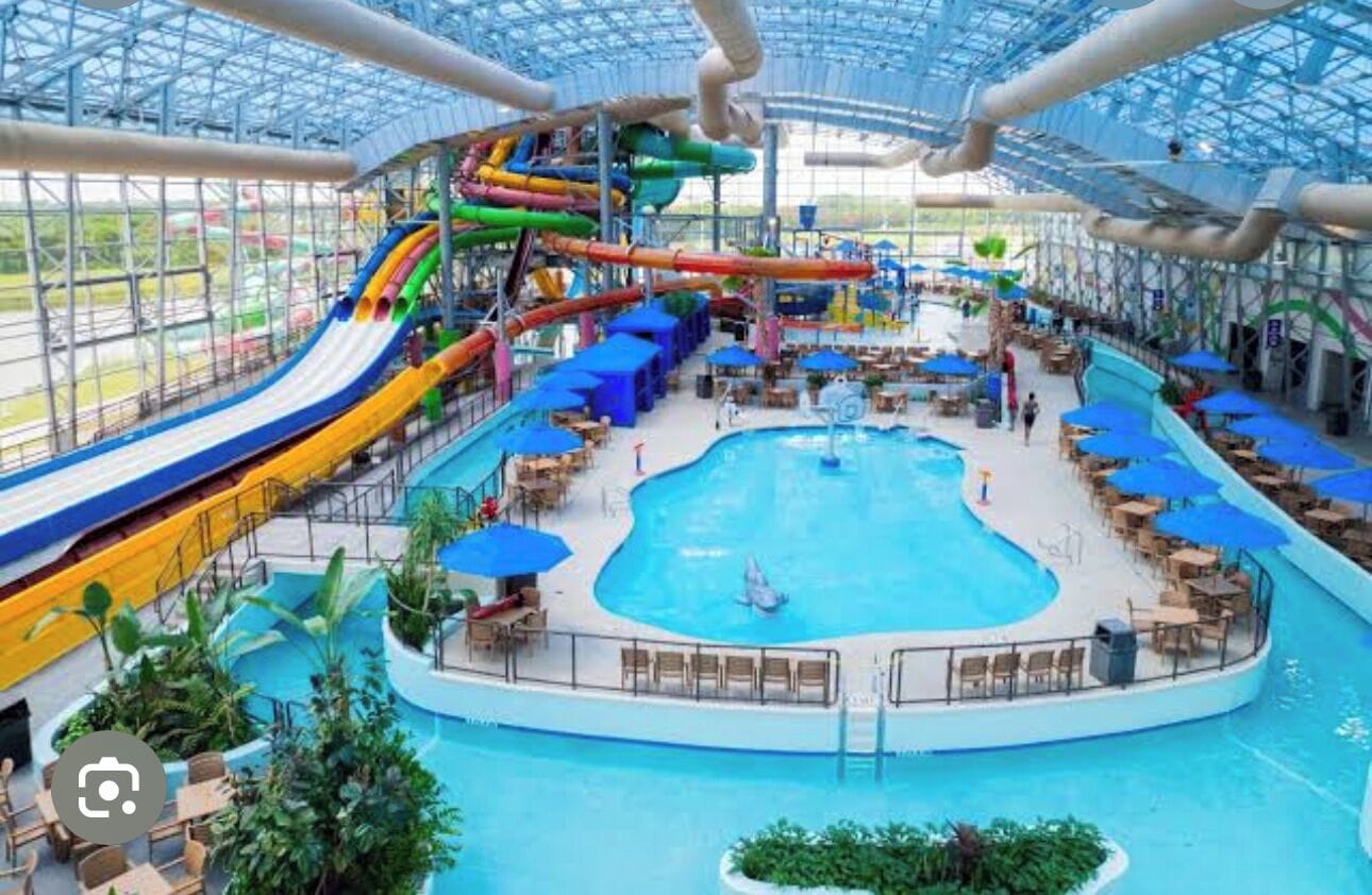 An indoor water park with a large pool, slides, and seating areas.