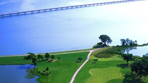 Vue aérienne d’un terrain de golf avec un pont en arrière-plan.