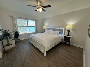 A bedroom with a bed, bedside lamps, a ceiling fan, a window with blinds, a chair, and a potted plant. - Lakeside Getaway Near AT&T Stadium, Globe Life, Six Flags & Epic Waters (Grand Prairie)