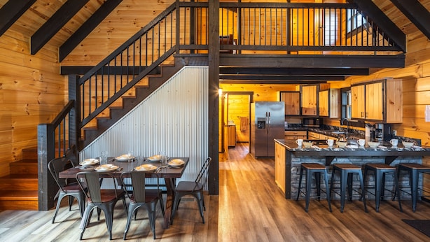 A spacious kitchen with a central island, wooden floors, and a staircase leading to an upper level. - Schilling Hill (New Philadelphia)