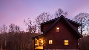 A wooden cabin with a stone foundation, a porch, and a stone wall surrounding the property. - Schilling Hill (New Philadelphia)