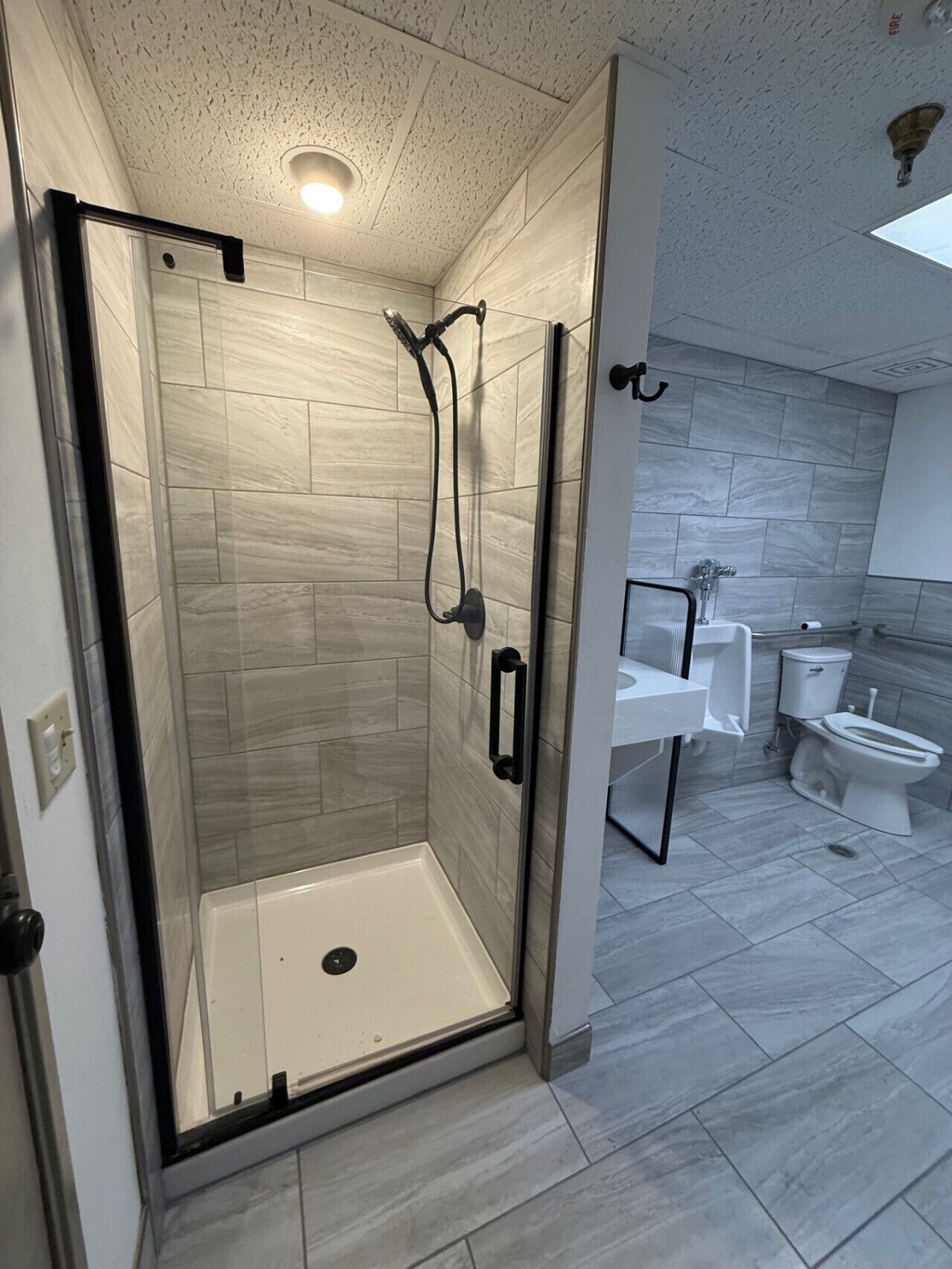 A modern bathroom with a glass-enclosed shower, a toilet, and a sink.