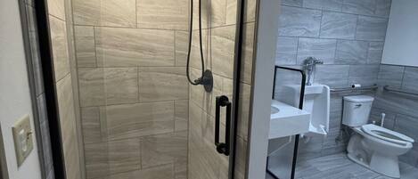 A modern bathroom with a glass-enclosed shower, a toilet, and a sink.