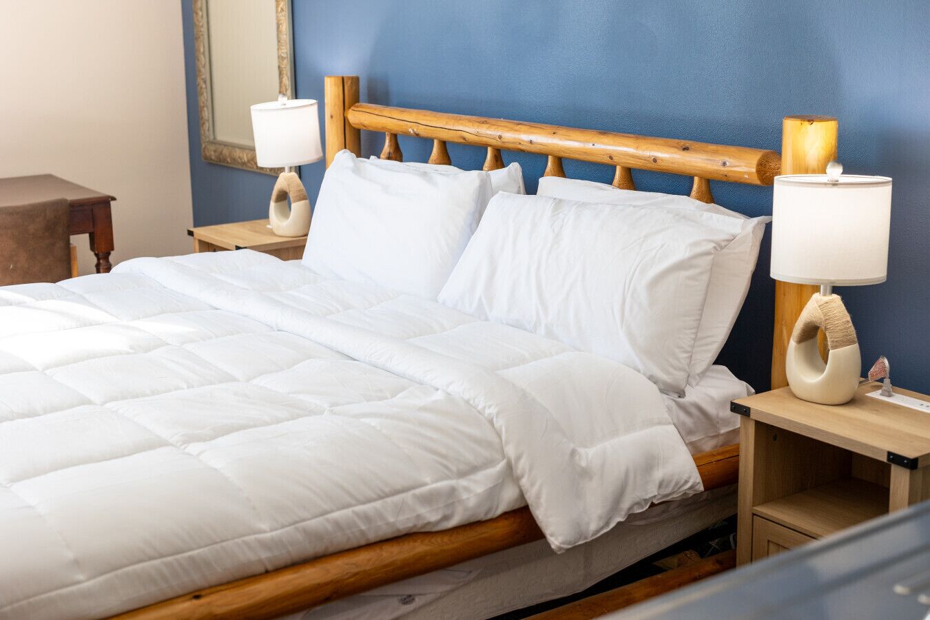 A neatly made bed with white bedding, wooden headboard, and two bedside lamps on wooden nightstands.