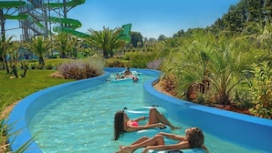 A pool with two people lying on inflatable tubes, surrounded by lush greenery and a water slide in the background. - Beach House BET, romantisches Refugium im Olivenhain by Interhome (Pula/Banjole)