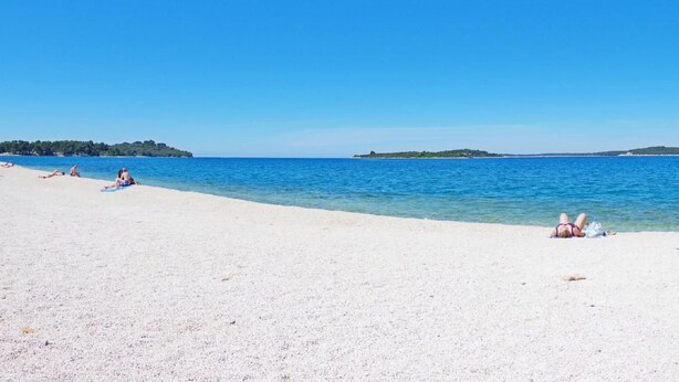 Ein Strand mit klarem, blauem Wasser und einem sandigen Ufer.