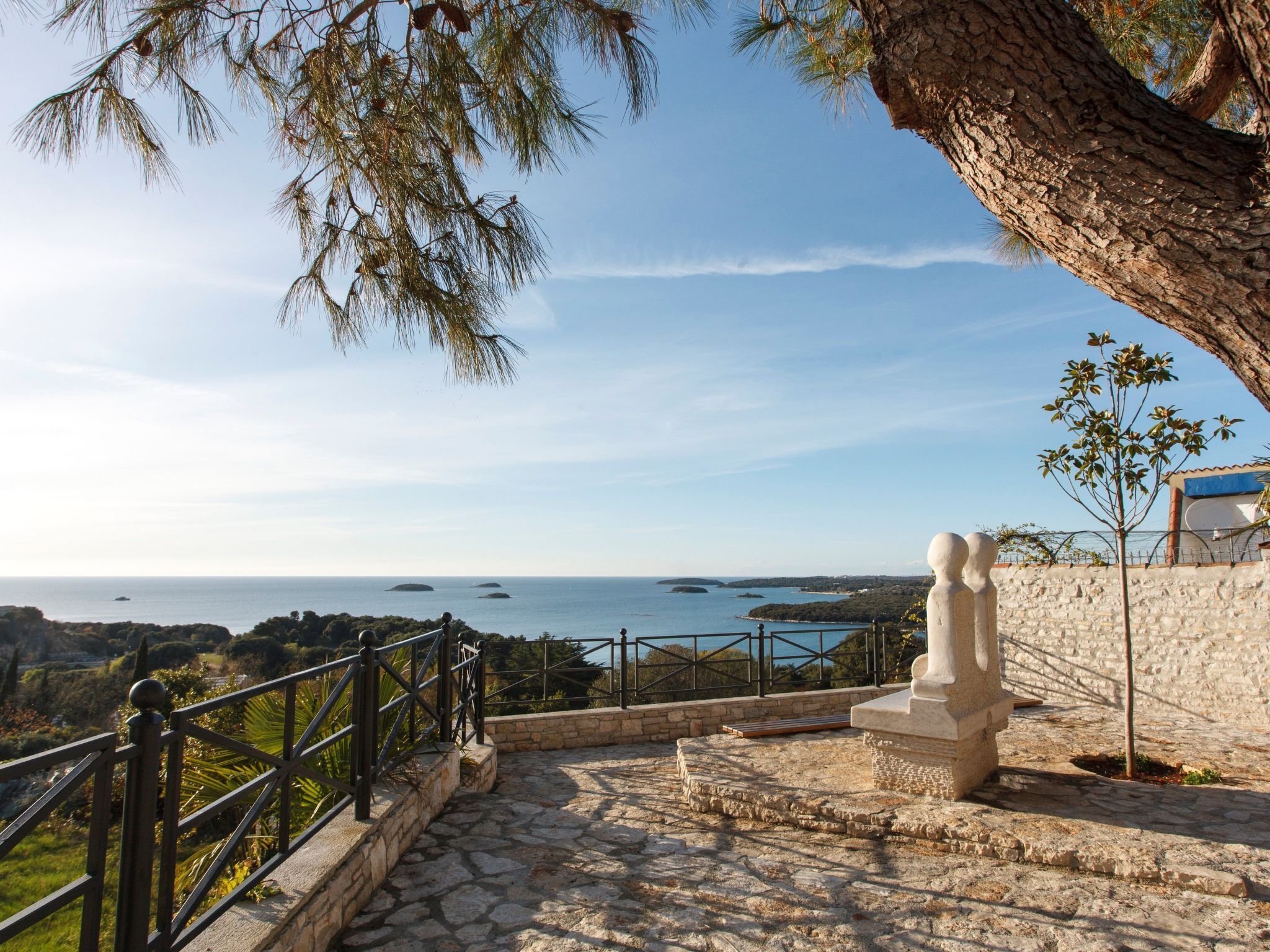 A stone staircase leading to a scenic overlook with a view of the sea and distant islands.