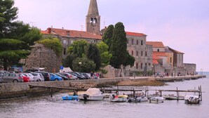 A coastal town with a prominent church tower, stone buildings, and a marina with boats.