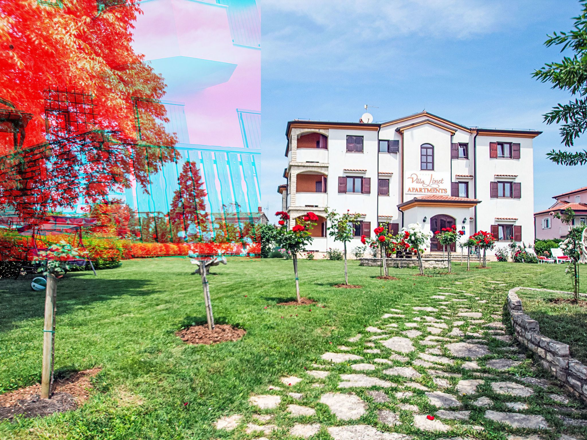 Villa Lint Apartments with a garden, stone pathway, and red flowers.