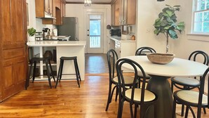 Een keuken met houten kastjes, een centraal eiland en een eethoek met stoelen en een tafel.