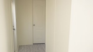 A narrow hallway with a white door at the end, light-colored wooden flooring, and a ceiling light fixture. - 3BR FOREST NEST in Columbus, GA (Columbus)