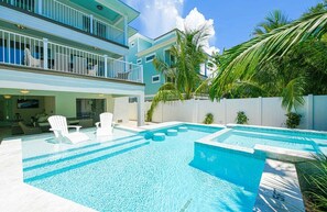 A pool area with lounge chairs and a two-story building with balconies. - Siesta Key Luxe w/ Pool, Rooftop & Steps to Beach (Siesta Key)