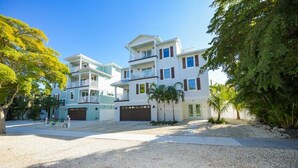 A multi-story residential building with a driveway, a garage, and a well-maintained lawn. - Siesta Key Luxe w/ Pool, Rooftop & Steps to Beach (Siesta Key)