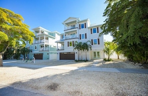A multi-story residential building with a driveway, a garage, and a well-maintained lawn.