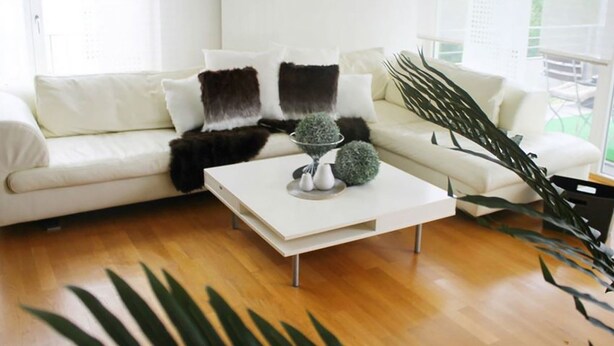Een moderne woonkamer met een witte bank, een salontafel en een groot raam.