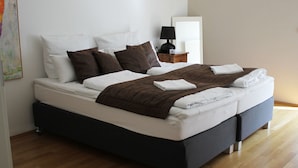 Een moderne slaapkamer met een bed, kussens, een nachtkastje en een lamp.