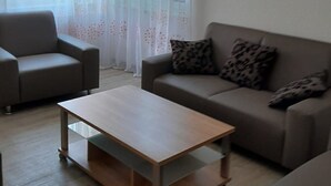 Een woonkamer met een bank, een fauteuil en een salontafel.