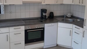 Een moderne keuken met witte kasten, een ingebouwde oven, een vaatwasser en een koffiezetapparaat.