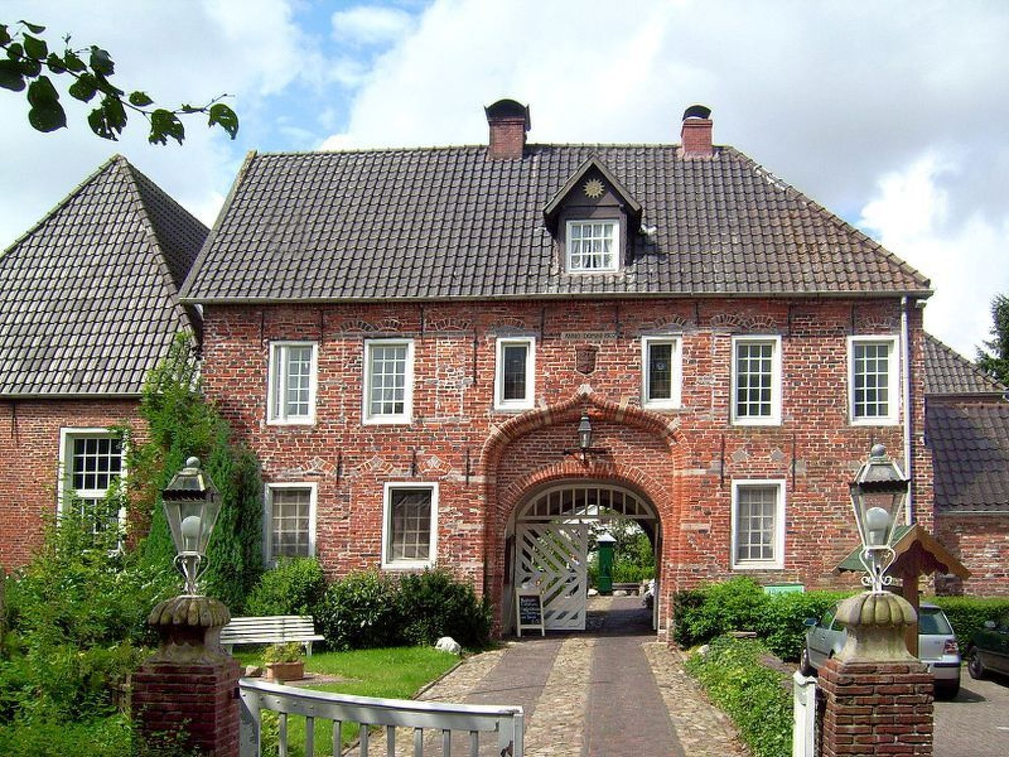 A traditional brick building with a symmetrical facade, a central arched entrance, and a tiled roof.