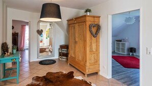 Un vaste salon agrémenté d’un grand tapis en peau de vache, d’un meuble en bois orné d’un motif en forme de cœur et d’un miroir qui reflète la pièce.
