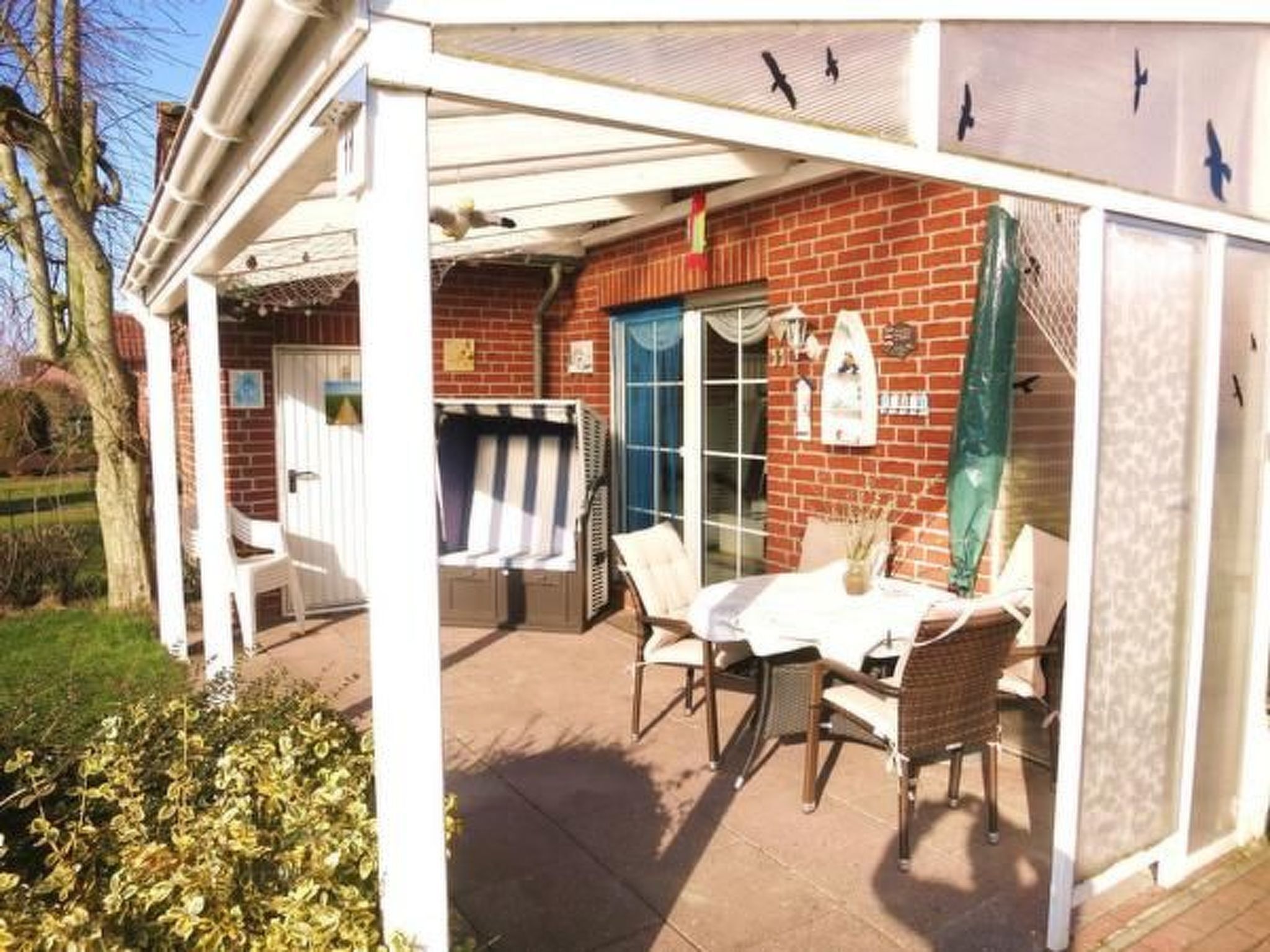 An outdoor patio with a table and chairs, a covered seating area, and a brick wall.