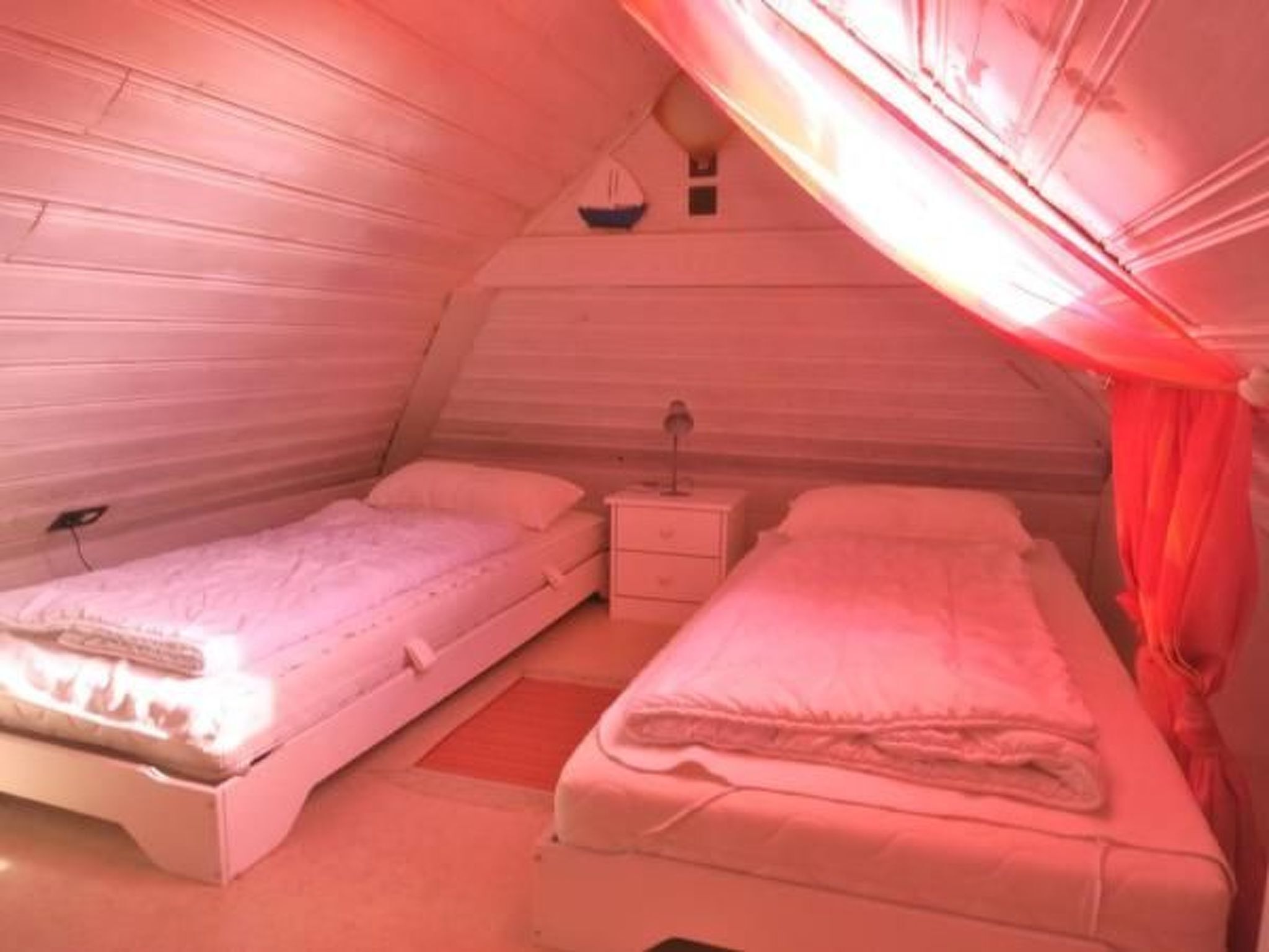 Een slaapkamer met twee bedden, een nachtkastje en een wandlamp.
