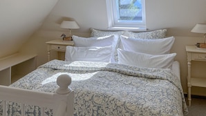 Une chambre à coucher avec un lit, deux tables de chevet, une fenêtre et une lampe.