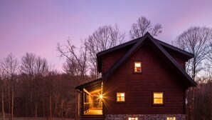 Une cabane en bois avec des fondations en pierre, une véranda et un ciel dégagé.