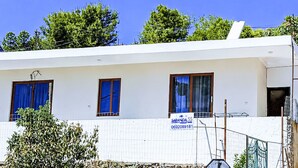 Un edificio con tres ventanas, un letrero y un cielo azul despejado.