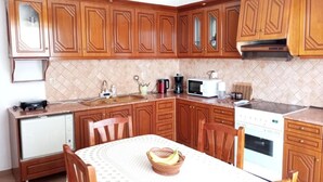 Cocina compacta con armarios de madera, microondas, cafetera y lavavajillas.