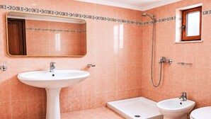 Un baño con lavamanos pedestal, ducha, bidé e inodoro.
