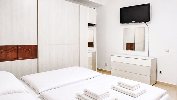 Habitación de hotel con cama, cómoda, televisor y espejo.