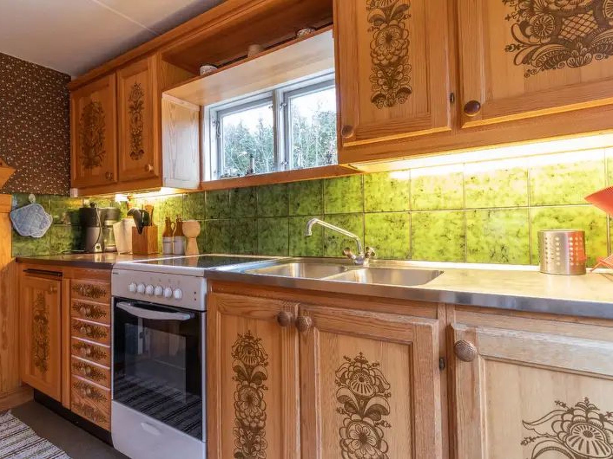 A kitchen with wooden cabinets, a built-in oven, a stainless steel sink, and a window above the sink.