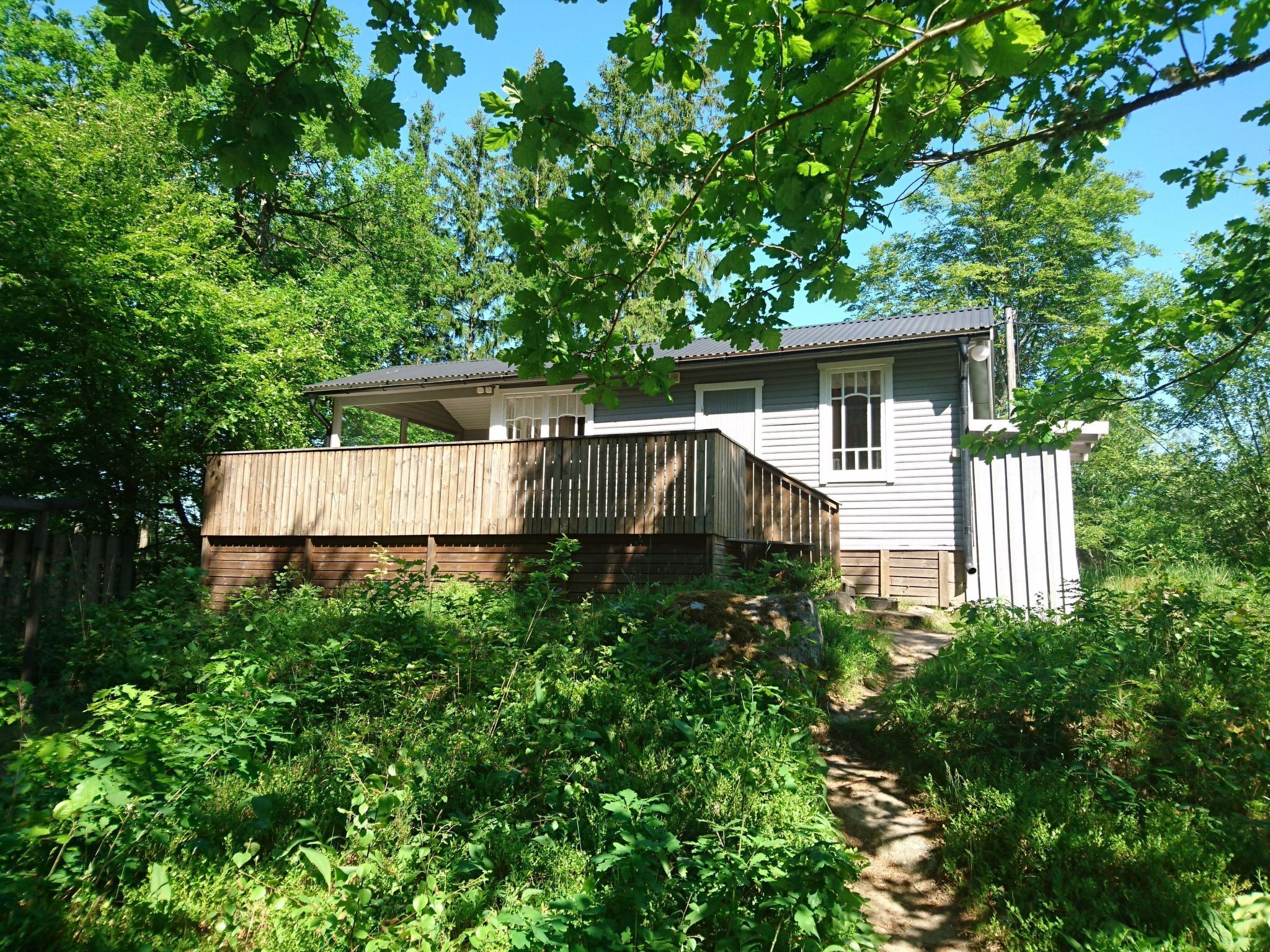 A house with a wooden deck, a covered porch, and a small garden area.